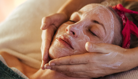 A woman receiving a facial massage with cream on her face.